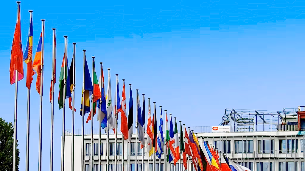 Bir dizi ülke bayrağı, bayrak direklerinde gökyüzüne karşı dalgalanıyor