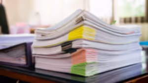 Renkli ayraçlarla düzenlenmiş büyük belge yığını masada bekliyor